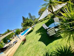a swimming pool with two lawn chairs and an umbrella at Quinta Alfaval in Redondo
