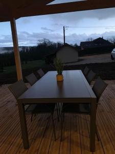 una mesa con sillas y una maceta en un patio en Gîte chalet, Au Doubs Logis, en Pierrefontaine-les-Varans