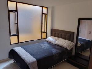 Dormitorio pequeño con cama y espejo en Linda habitación amplia iluminada Bogota Calle 80, en Bogotá