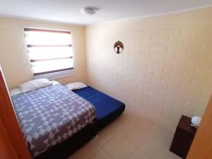 a small bedroom with a bed and a window at Casa en Padre Hurtado IV in Talagante
