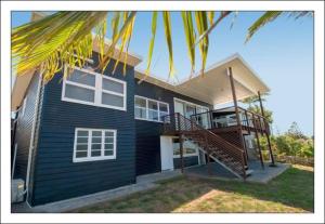 a blue house with a staircase in front of it at Seacrest on Bright in Emu Park