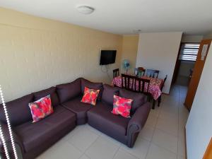 a living room with a brown leather couch with pillows at Agradable casa en Padre Hurtado VI in Talagante