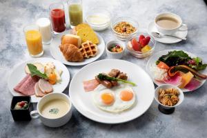 a table with plates of breakfast foods and drinks at Hotel Kanazawa in Kanazawa