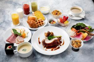 a table with plates of breakfast foods and drinks at Hotel Kanazawa in Kanazawa