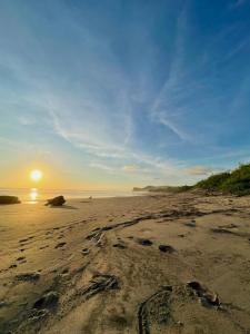 una playa con huellas en la arena al atardecer en Casa Mariposa en Tola