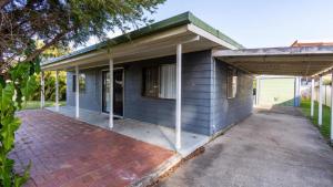 ein blaues Haus mit einer gepflasterten Auffahrt davor in der Unterkunft Dog Friendly Holiday House In Bongaree in Bongaree