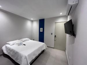 1 dormitorio con 1 cama blanca y TV de pantalla plana en Loft 33 en Monterrey