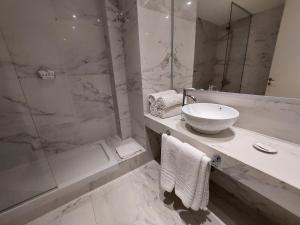 a white bathroom with a sink and a shower at Avellaneda Aparts & Suites in Buenos Aires