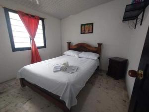 - une chambre avec un lit doté de draps blancs et une fenêtre dans l'établissement Casa Hostal M&M, à Norcasia