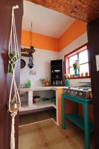 cocina con paredes de color naranja y mesa azul en Casa Flor de Vida en San Cristóbal de Las Casas