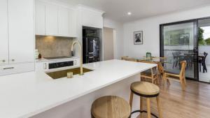 cocina con encimeras blancas y comedor en Beach Shack Bongaree, en Bongaree