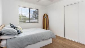 un dormitorio con una cama y una ventana en Beach Shack Bongaree, en Bongaree