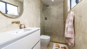 Un baño con lavabo, inodoro y espejo. en Beach Shack Bongaree, en Bongaree 13 fotos más