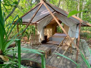 TandulujanggaCamp Tarimbang的树林里带椅子和床的帐篷