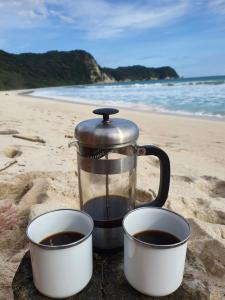 eine Kaffeemaschine und zwei Tassen am Strand in der Unterkunft Camp Tarimbang in Tandulujangga