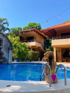 Una donna in bikini seduta accanto alla piscina di Hotel Costa Coral a Tambor