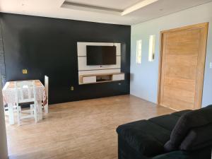a living room with a couch and a tv on a wall at Casa Angra vista pro mar in Angra dos Reis