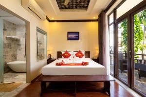 a bedroom with a bed and a tub in a room at Little Town Villa in Hoi An