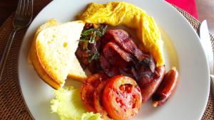 a plate of food with a sandwich and tomatoes at Tirta Ayu Hotel and Restaurant in Tirtagangga