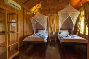 a bedroom with two beds with mosquito nets at K2 Lembeh Dive Resort in Bitung