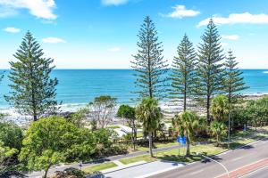 an aerial view of a road with palm trees and the ocean at Windward Apartments in Mooloolaba