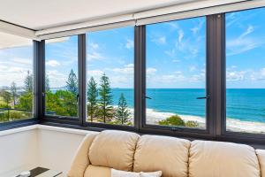 a couch in a room with windows looking out at the ocean at Windward Apartments in Mooloolaba