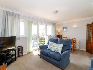 uma sala de estar com uma cadeira azul e uma televisão em Lookout em Weymouth