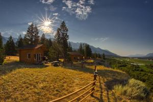 a wooden cabin in a field with a fence at The Raven's Nest Resort & Campground in Fairmont Hot Springs
