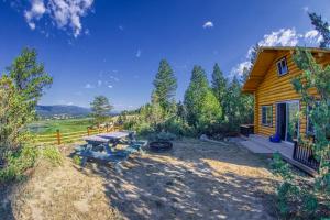 a wooden cabin with a picnic table and a grill at The Raven's Nest Resort & Campground in Fairmont Hot Springs
