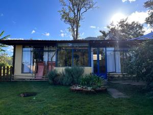 a house with a large window and a yard at Casinha Limão Escondido in Sapucaí-Mirim