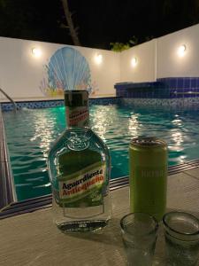 a bottle of alcohol sitting on a table next to a swimming pool at HOTEL ARRECIFE in Santa Veronica