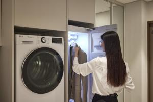 a woman is standing next to a washing machine at The Connoisseur Residence Hotel in Seoul