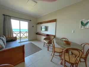 a living room with a table and chairs and a view of the ocean at Morada Baden Baden in Bombinhas