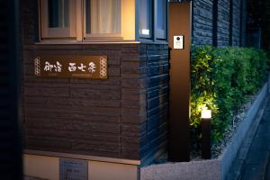 un panneau sur le côté d'un bâtiment dans l'établissement Oyado Nishishichijo, à Kyoto