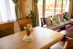 einen Holztisch mit einer Vase mit Blumen darauf in der Unterkunft 貸別荘Clover　天城杉のログハウス　伊豆高原 in Ito