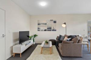 een woonkamer met een bank en een tv bij A Comfy & Cozy 2BR Apt Near Flemington Races in Melbourne