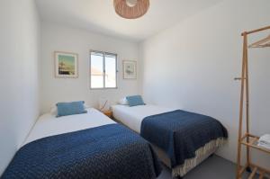 Duas camas num quarto branco com lençóis azuis em Comporta Sandy Villa, By TimeCooler em Comporta