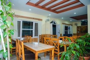 Un comedor con mesas y sillas de madera. en Hotel Olympus Pokhara, en Pokhara