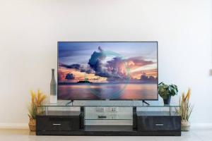 una TV a schermo piatto seduta su un centro di intrattenimento in vetro di ZEN At ARRAY: 2BR Retreat in CBD a Darwin
