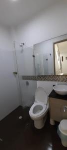 a bathroom with a toilet and a sink and a mirror at Casa frente al mar con piscina in Coveñas