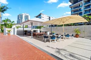 a patio with tables and chairs and an umbrella at Windward Apartments in Mooloolaba