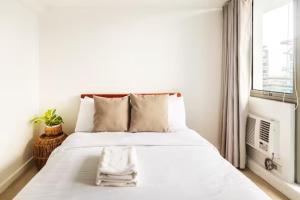 - un lit blanc dans une chambre avec fenêtre dans l'établissement Sabrina's Crib Apartment 2BR by Azure Residences Near Airport, à Manille