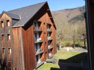 a large wooden building with a balcony and a mountain at Appartement Bagnères-de-Luchon, 2 pièces, 4 personnes - FR-1-313-222 in Luchon