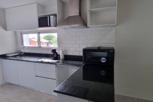 een keuken met witte kasten en een zwart aanrecht bij Zona aeropuerto dpto a estrenar! 202 in La Mercedes