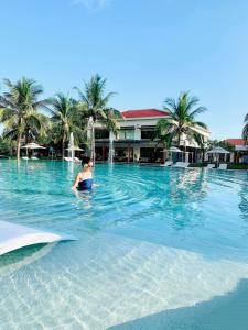 a woman sitting in the water in a swimming pool at Luxury Beach Resort Da Nang in Da Nang