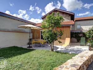 een patio met een parasol en een tafel en stoelen bij Gîte Balbigny, 3 pièces, 4 personnes - FR-1-496-282 in Balbigny