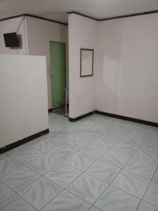 Habitación con paredes blancas y suelo de baldosa. en Vina Vira Hotel en Hagu