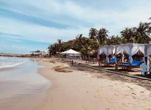 a beach with chairs and umbrellas and the ocean at Hermoso Apartamento Cerca a la Playa Puerto Colombia in Puerto Colombia