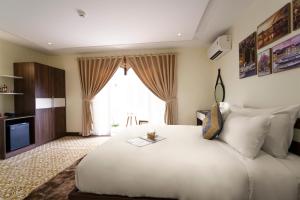 1 dormitorio con 1 cama blanca grande y TV en Hawal Boutique Villa Hoi An en Hoi An