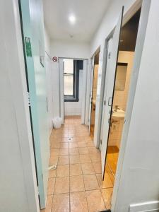 um corredor de uma casa de banho com piso em azulejo em The Downing Hostel em Sidney